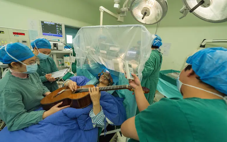 Un musicien chinois joue de la guitare durant son opération du cerveau