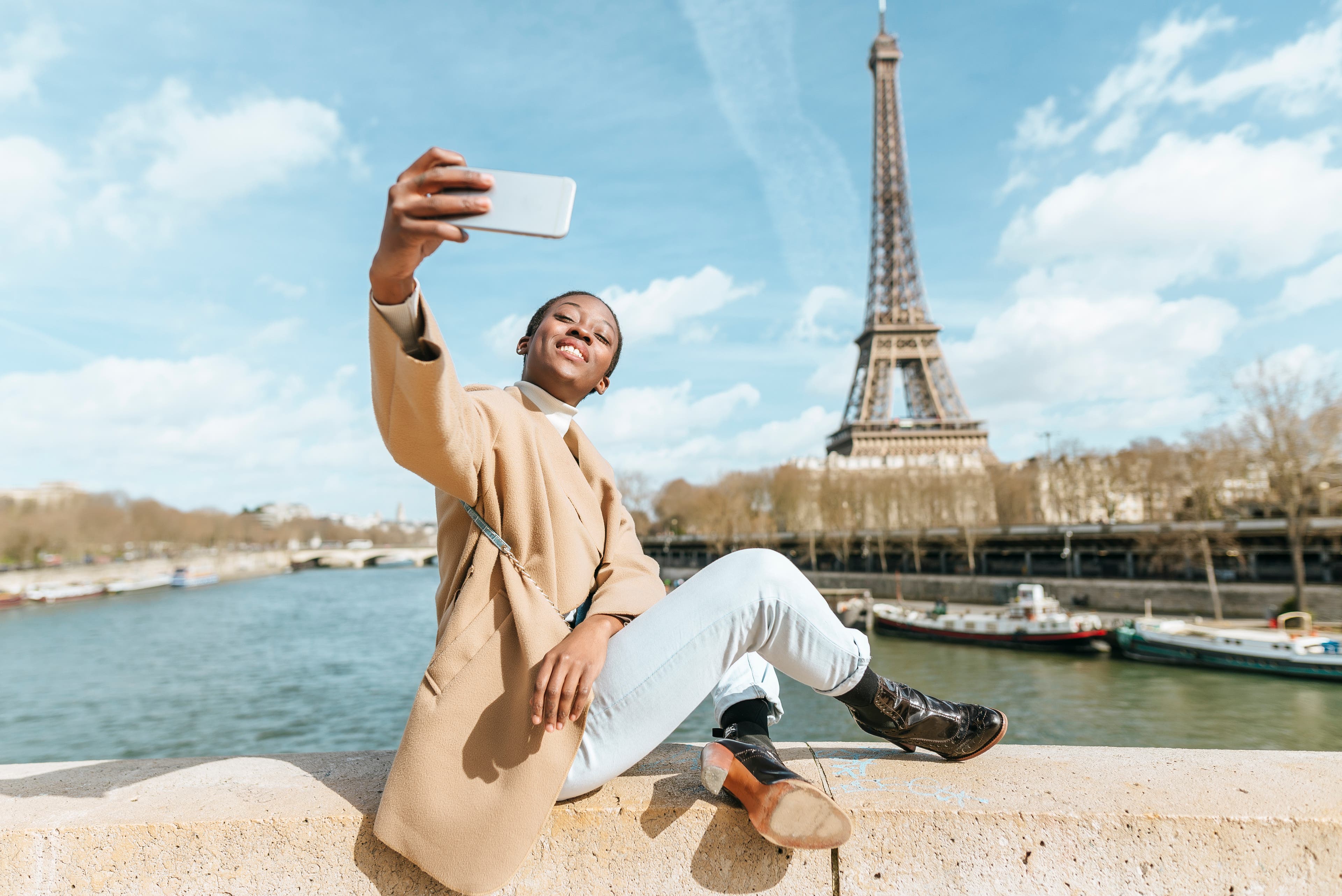Femme se prenant en selfie avec la Tour Eiffeil en arrière-plan.