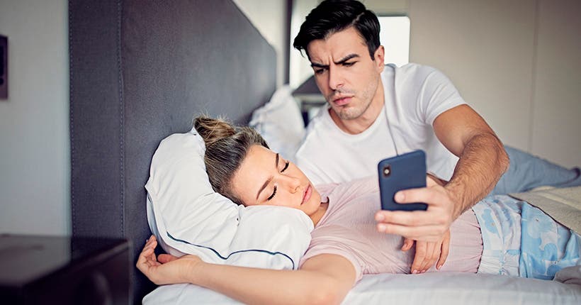 <p>Jealous husband is checking his sleeping wife`s mobile phone</p>

