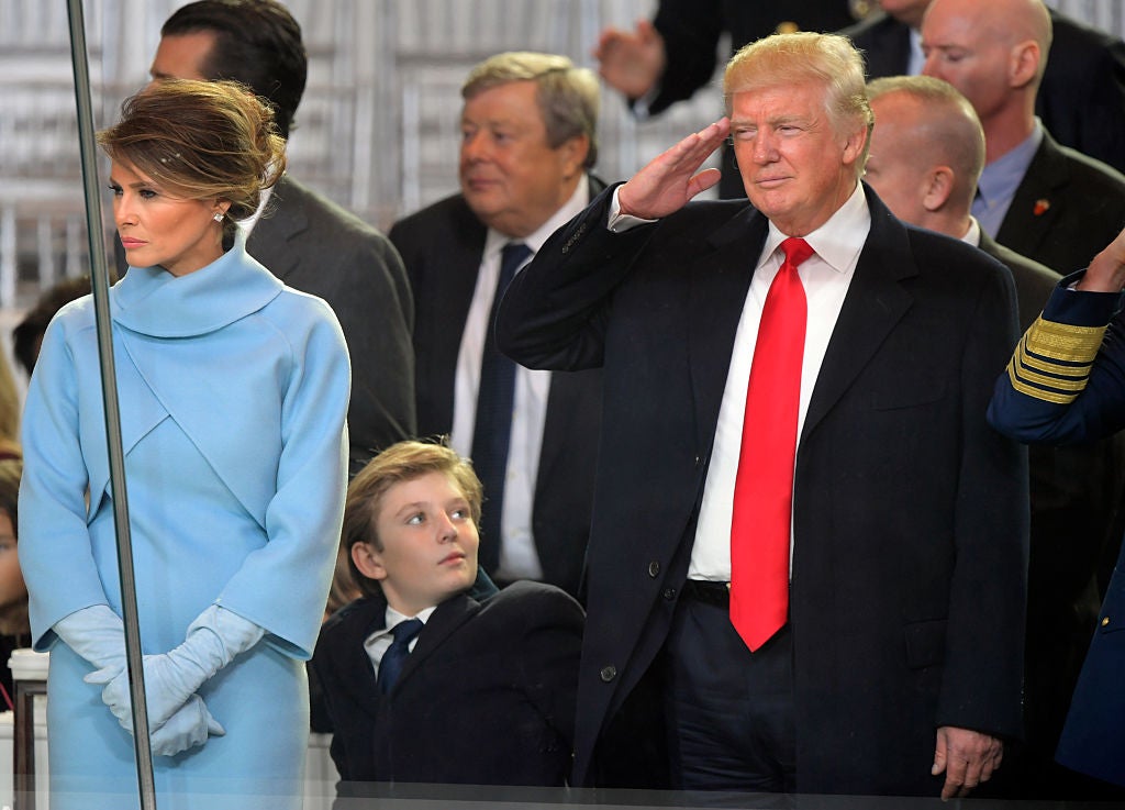 WASHINGTON DC, JANUARY 20: Newly sworn in President Donald Trump, right, salutes the Coast Guard marching in formation during the Inaugural parade. His wife Melania, left, and son Barron share a front row seat in the reviewing stand in front of the White House in Washington DC, January 20 2017. (Photo by John McDonnell / The Washington Post via Getty Images)